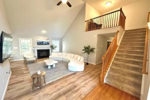 a living room with a white couch and a staircase at Lake Anna Lakeside Luxury 6BR w Game Room, Cinema, Hot tub and Grill in Bumpass