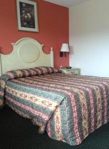 Una habitación de hotel con una cama con una manta encima. en New Orleans Inn, en Nueva Orleans 15 fotos más