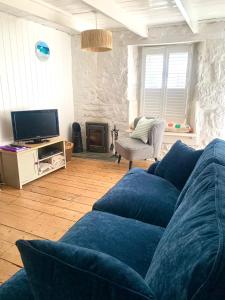 een woonkamer met een blauwe bank en een tv bij Newlyn Harbour Cottage in Newlyn