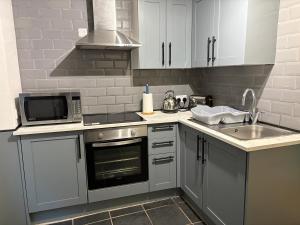 een keuken met witte kasten, een spoelbak en een magnetron bij Newlyn Harbour Cottage in Newlyn