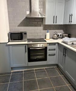 een keuken met witte kasten en een kookplaat oven bij Newlyn Harbour Cottage in Newlyn +22 foto's