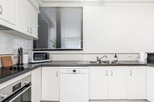 a white kitchen with a sink and a microwave at Karingal 1 in Lennox Head