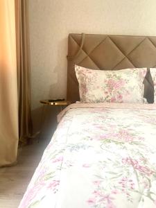 a bedroom with a bed with pink flowers on it at Комфортабельные - уютные апартаменты в Костанай Береке 63 in Kostanay