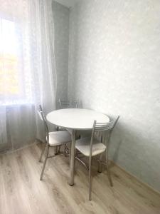 a white table and chairs in a room with a window at Комфортабельные - уютные апартаменты в Костанай Береке 63 in Kostanay