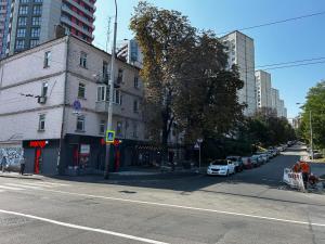 an empty city street with a white car parked next to a building at Apartment near train station and close to city center in Kyiv