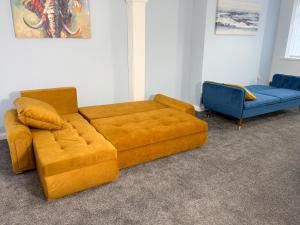 a living room with a yellow couch and a blue chair at Millbrook Blues 2BR Entire Home in Middlesbrough