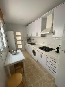 a kitchen with white cabinets and a table and a stove at Santa Ana in Novo Sancti Petri