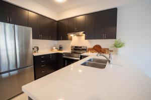 a kitchen with black cabinets and a stainless steel refrigerator at The Cozy Corner in Hamilton