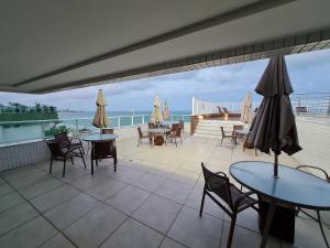 a patio with tables and chairs and a view of the ocean at Pacific Flat da Miramar in Tambaú
