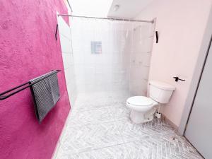 a bathroom with a toilet and a pink wall at Shanti Home in Tepoztlán