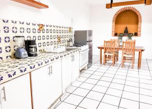 a kitchen with white cabinets and a table and chairs at Shanti Home in Tepoztlán