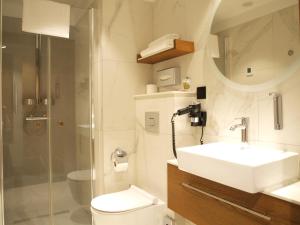 een badkamer met een wastafel, een toilet en een douche bij Gvarna Apartamenty in Wrocław