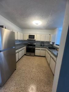a kitchen with white cabinets and a stainless steel refrigerator at relax house in San Lorenzo