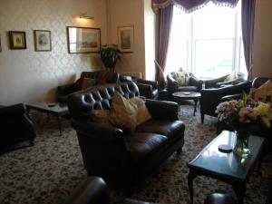 a living room with leather couches and a large window at Headlands Hotel in Llandudno