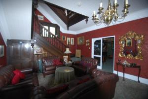 a living room with red walls and leather furniture at Headlands Hotel in Llandudno