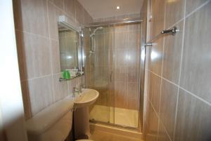 uma casa de banho com um chuveiro, um WC e um lavatório. em Headlands Hotel em Llandudno