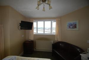a bedroom with a bed and a television and a window at Headlands Hotel in Llandudno