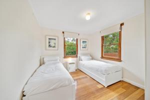 a bedroom with two beds and two windows at Comfortable 3-Bed Haven Near Canberra Attractions in Narrabundah