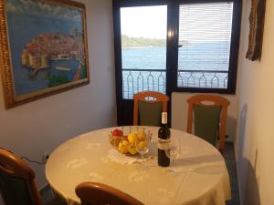 a table with a bottle of wine and a bowl of fruit at Apartments "Villa Mungos" Sobra in Sobra