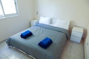 a bedroom with a bed with two blue pillows on it at Mackenzie Apartment 101 in Larnaka