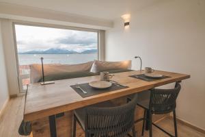 a dining room table with chairs and a large window at Loft By Toore Patagonia in Puerto Natales