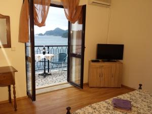a room with a door open to a balcony with a television at Apartments "Villa Mungos" Sobra in Sobra