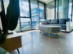 a living room with a couch and a large window at Modern stylish 3 bedroom condo - Parking, Gym, Pool in Sydney