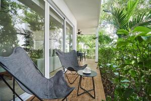 Un patio con dos sillas y una mesa y algunas plantas. en Aldea Zama Condo with 2 Pools, Gym, Yoga Deck and BBQ Grill, en Tulum