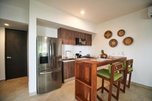a kitchen with a wooden table and a stainless steel refrigerator at Zama Condo with 2 Pools, Gym, Yoga Deck and BBQ Grill in Top Location in Tulum