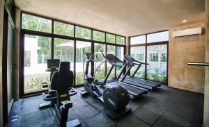 a gym with several tread machines in a room with windows at Aldea Zama Condo with 2 Pools, Gym, Yoga Deck and BBQ Grill in Tulum
