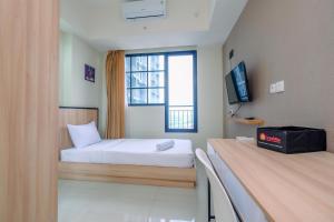 德波Nice 2BR at 26th Floor Evenciio Margonda Apartment By Travelio的一间有床和窗户的小房间