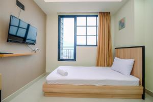 德波Nice 2BR at 26th Floor Evenciio Margonda Apartment By Travelio的一间带床、电视和窗户的卧室 更多18张照片