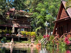 three girls sitting in the water in front of a house at Mondulkiri Pizza Bungalows in Sen Monorom
