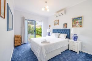 a bedroom with a white bed and a blue carpet at Tah Villa 1, 68 Marine Dr - stunning views, linen and air con in Fingal Bay