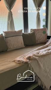 a bed with pillows on it with a window at Berdina casa estilo loft con jardín, parrilla y cochera a 3 cuadras de la plaza de Chacras de Coria in Chacras de Coria