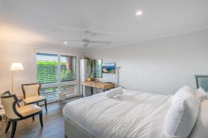 a white bedroom with a bed and two chairs at Kiama Mountain Views Studio in Kiama