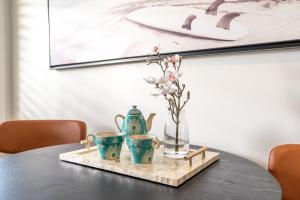 a table with a tray with three cups and a vase at Kiama Mountain Views Studio in Kiama