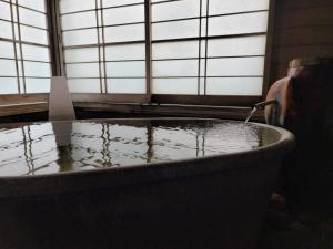 una vasca da bagno riempita d'acqua accanto a una finestra di Hanaichi a Tsumagoi