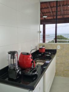 a kitchen counter with a red appliance on a stove at Ipê Amarelo - Frente ao Mar na Praia de Meaípe, Guarapari in Guarapari