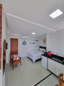 a bedroom with a bed and a kitchen with a sink at Ipê Amarelo - Frente ao Mar na Praia de Meaípe, Guarapari in Guarapari