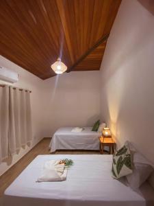 a bedroom with two beds and a wooden ceiling at Village da Mata Arraial in Porto Seguro