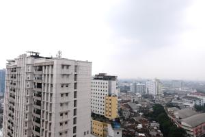 a tall white building in a city with buildings at Homey and Spacious 3BR Apartment at Braga City Walk By Travelio in Bandung