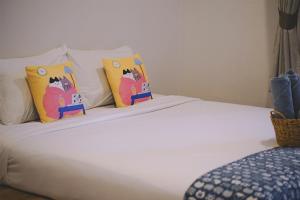 a white bed with three pillows on top of it at Sleepy House Chiang Rai in Chiang Rai