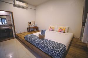 a bedroom with a large white bed with a bench at Sleepy House Chiang Rai in Chiang Rai