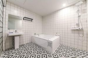 平泽市Pyeongtaek Gallery Hotel的配有浴缸和水槽的白色瓷砖浴室