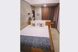 a bedroom with two beds with white sheets and pillows at Sleepy House Chiang Rai in Chiang Rai