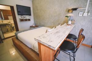 チェンライにあるSleepy House Chiang Raiのベッド、テーブル、椅子が備わるホテルルームです。