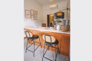 a kitchen with a bar with three stools at Sleepy House Chiang Rai in Chiang Rai