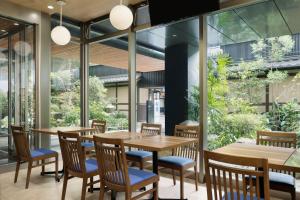 a restaurant with wooden tables and chairs and large windows at Four Points Flex by Sheraton Kyoto Oike in Kyoto