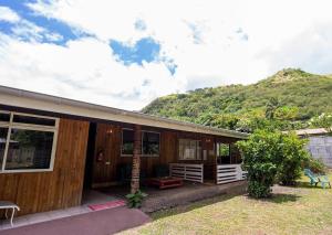 a wooden house with a mountain in the background at PENSION TE MITI hebergement touristique TAHITI - plage a 200m in Punaauia